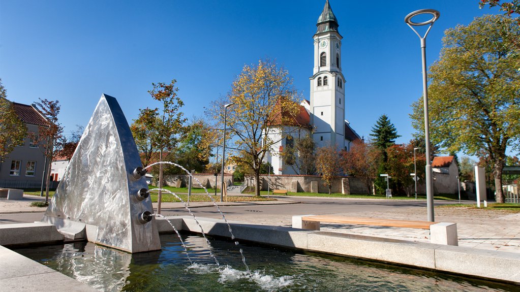 Dorfplatz mit Brunnen und Kirche